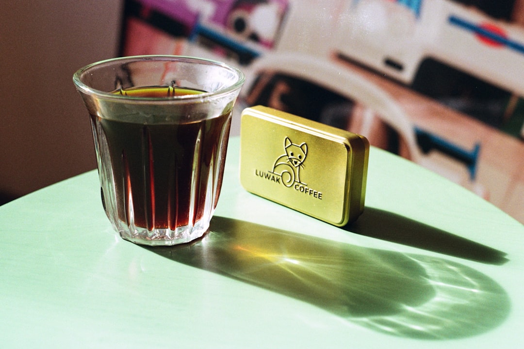 glass-of-coffee-next-to-a-small-golden-tin-v12s43qb2aq